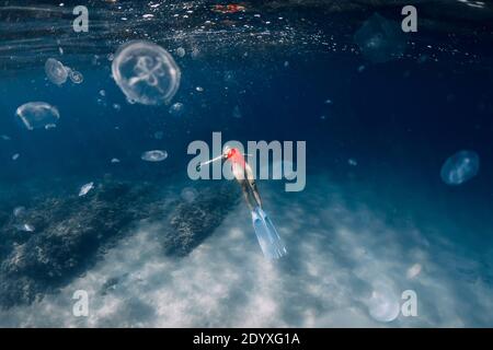 Frau Freitaucher mit weißen Flossen und Quallen unter Wasser. Freitauchen mit Quallen im blauen Ozean Stockfoto