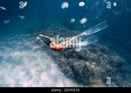 Frau Freitaucher mit weißen Flossen und Quallen unter Wasser. Freitauchen mit Quallen im blauen Ozean Stockfoto