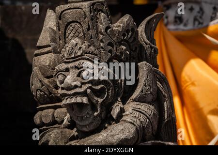 Nahaufnahme eines Dvarapala (Torhüter) Statue am Tanah Lot Tempel auf orangefarbenem Hintergrund Stockfoto