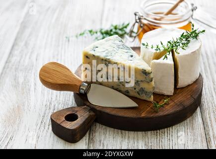 Verschiedene Käsesorten, Blauschimmelkäse, bree, Camambert und Honig auf einem Holztisch Stockfoto