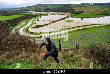 Alfriston Sussex UK 28. Dezember 2020 - EIN Wanderer klettert einen Pfad hinauf, nachdem er über Felder und Ackerland geschaut hat, die vom Fluss Cuckmere in der Nähe von Alfriston in East Sussex überschwemmt werden, nachdem der kürzliche heftige Regen und der Sturm Bella für Störungen in ganz Großbritannien gesorgt haben. Mehr Schnee und Regen werden für Großbritannien in den nächsten Tagen prognostiziert : Credit Simon Dack / Alamy Live News Stockfoto