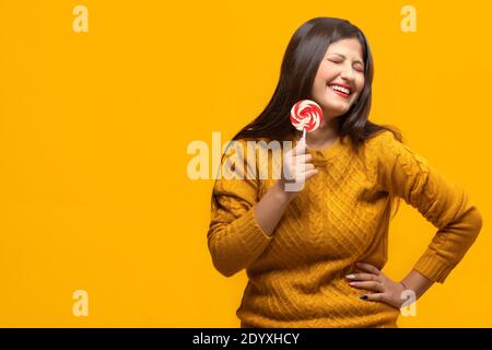 Junge Frau, die lachend einen Lutscher in der Hand hält Stockfoto