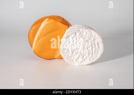 Zwei ganze Köpfe, Käserad, Brie und geräucherter Käse suluguni auf weißem Hintergrund. Nahaufnahme Stockfoto