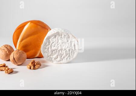Zwei ganze Köpfe, Käserad, Brie und geräucherter Käse suluguni auf weißem Hintergrund. Nahaufnahme, Kopierraum Stockfoto
