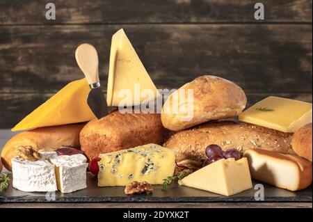 Käse und Brot. Viele Arten von Brot und Käse auf Holz rustikalen Hintergrund. Käseplatte, Verkostung und Paarung. Ein Sortiment verschiedener Arten von c Stockfoto