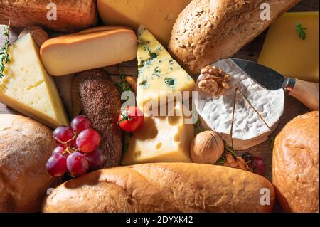 Käse und Brot Hintergrund. Viele Arten von Brot und Käse. Käseplatte, Verkostung und Paarung. Eine Auswahl verschiedener Käsesorten, Weintrauben, Wal Stockfoto