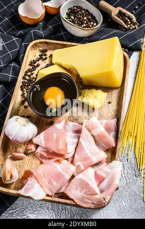 Traditionelle Italienische Pasta Carbonara Zutaten. Speck, Spaghetti, Parmesan und Pecorino Käse, Ei, Knoblauch. Grauer Hintergrund. Draufsicht Stockfoto