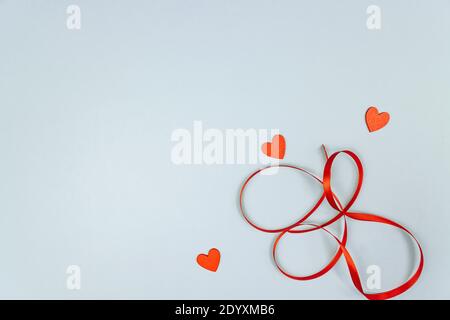 Herz mit roten Pailletten und Satinband auf blauem Hintergrund. Kreatives minimales Layout mit Platz für die Kopie zum Valentinstag Stockfoto