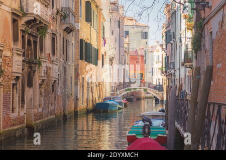 Sonnenschein und Boote entlang eines ruhigen, bunten Kanals in Venedig, Italien. Stockfoto