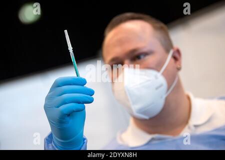 Bremen, Deutschland. Dezember 2020. Ein Mitarbeiter des Impfzentrums hält eine Spritze mit dem Covid 19-Impfstoff. Das Bremer Impfzentrum in der Messehalle 7 hat seinen Betrieb aufgenommen. Quelle: Sina Schuldt/dpa/Alamy Live News Stockfoto