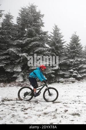 Ein Mann radelt im Mortimer Forest bei Ludlow in Shropshire durch den Schnee. Stockfoto