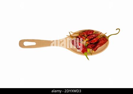 Getrocknete rote Chilischote liegt auf einem Holzlöffel, isoliert auf weißem Hintergrund. Nahaufnahme Stockfoto