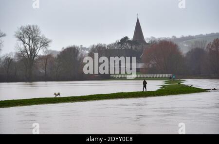 Alfriston Sussex UK 28. Dezember 2020 - Hundewanderer trotzen dem nassen Wetter, da Felder und Ackerland durch den Fluss Cuckmere in der Nähe von Alfriston in East Sussex überschwemmt werden, nachdem der kürzliche heftige Regen und Sturm Bella zu Störungen in ganz Großbritannien geführt hat. Mehr Schnee und Regen werden für Großbritannien in den nächsten Tagen prognostiziert : Credit Simon Dack / Alamy Live News Stockfoto