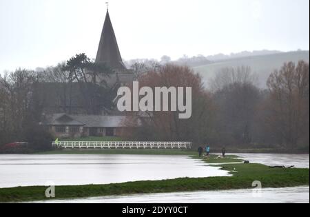 Alfriston Sussex UK 28. Dezember 2020 - Hundewanderer trotzen dem nassen Wetter, da Felder und Ackerland durch den Fluss Cuckmere in der Nähe von Alfriston in East Sussex überschwemmt werden, nachdem der kürzliche heftige Regen und Sturm Bella zu Störungen in ganz Großbritannien geführt hat. Mehr Schnee und Regen werden für Großbritannien in den nächsten Tagen prognostiziert : Credit Simon Dack / Alamy Live News Stockfoto