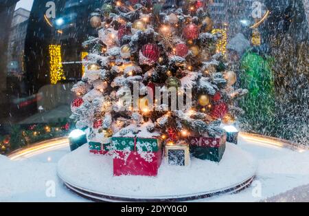 Ein Weihnachtsbaum mit Geschenken darunter, bedeckt mit frisch gefallener Schneedecke. Stockfoto