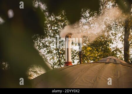 Ein rauchender Kamin aus einem Holzofen, der in einer Jurte auf einem campingplatz in glamp installiert ist. Stockfoto