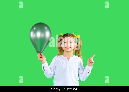 Kleinkind Mädchen mit Zöpfen hält eine ultimative graue Farbe Ballon, zeigt ihren Finger bis zu einem leeren Raum, wo Ihre Werbung sein kann. Hohe Qualität Stockfoto