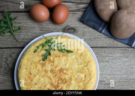 Spanische Lebensmittel Tortilla de Patatas oder spanische Kartoffel Omelette mit Frische Eier und Kartoffeln.Draufsicht hausgemachte klassische spanische Küche auf Holzhinterfuge Stockfoto