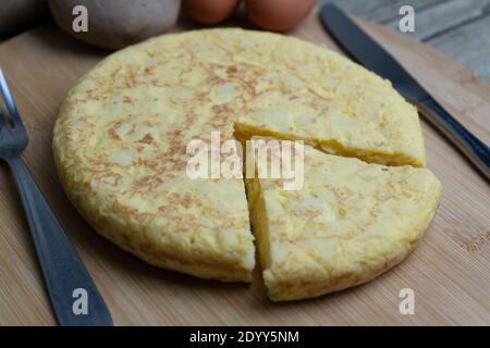 Geschnittene spanische Kartoffelomelette genannt Tortilla de Patatas mit Eiern und Kartoffeln auf Holzbrett.Typische spanische Küche.Tapas Hintergrund. Stockfoto