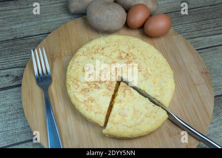 Geschnittene spanische Kartoffelomelette genannt Tortilla de Patatas mit Eiern und Kartoffeln auf Holzbrett.Typische spanische Küche.Tapas Hintergrund. Stockfoto