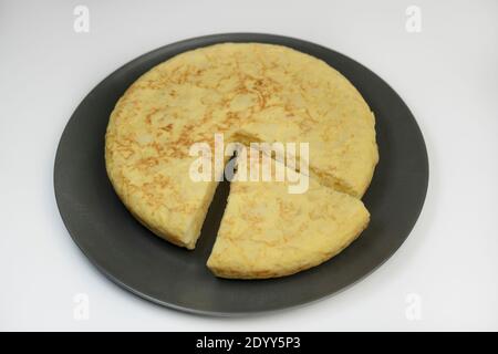 Tortilla de patatas oder spanische Kartoffelomelette auf dunklem Teller isoliert auf weißem Hintergrund. Stockfoto