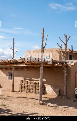 Lehmziegel aus Lehmziegeln stapelten sich neben einem lehmziegelhaus im historischen indianischen Dorf Taos Pueblo, New Mexico, USA. Ein UNESCO-Weltkulturerbe Stockfoto