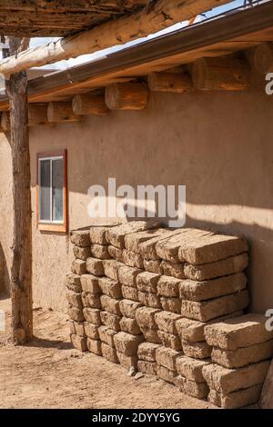 Lehmziegel aus Lehmziegeln stapelten sich neben einem lehmziegelhaus im historischen indianischen Dorf Taos Pueblo, New Mexico, USA. Ein UNESCO-Weltkulturerbe Stockfoto