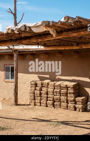 Lehmziegel aus Lehmziegeln stapelten sich neben einem lehmziegelhaus im historischen indianischen Dorf Taos Pueblo, New Mexico, USA. Ein UNESCO-Weltkulturerbe Stockfoto