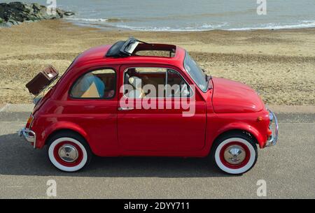 Classic Red Fiat 500 Auto mit Picknickkorb an der Strandpromenade geparkt. Stockfoto