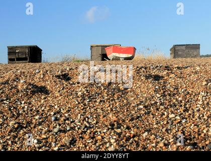 Fischerboot und Hütten am Strand von Dunwich, Suffolk Stockfoto