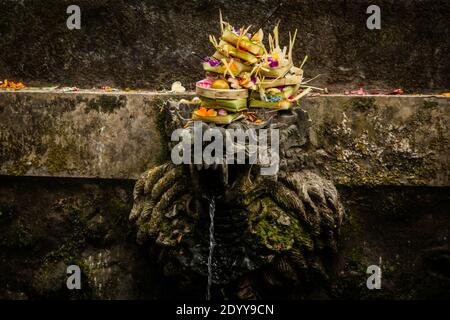 Farbenfrohe hinduistische Opfergaben auf einem Brunnen im Batukaru-Tempel Stockfoto