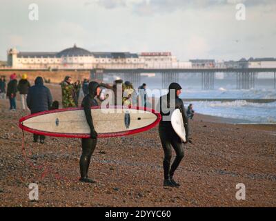 Surfer machen sich bereit, in das Meer auf einem zu gehen Wintertag in Brighton Stockfoto