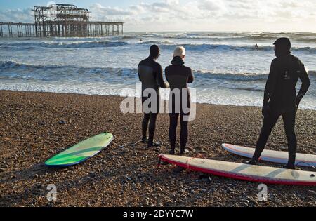 Surfer machen sich bereit, in das Meer auf einem zu gehen Wintertag in Brighton Stockfoto