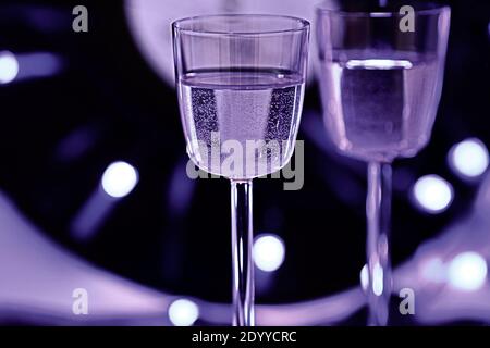 Selektiver Fokus Foto von zwei Gläsern Champagner auf dem Hintergrund einer Vinyl-Platte, umgeben von hellen Club Beleuchtung Stockfoto