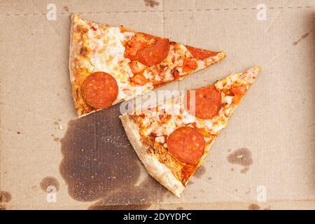 Nahaufnahme Reste von zwei Stück Pizza mit Pfefferoni und Tomaten in einem Karton. Draufsicht. Stockfoto