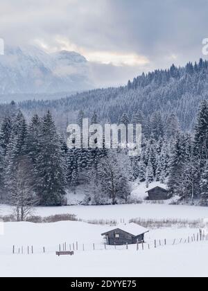 Winterliche vertikale Sicht auf schneebedeckte Holzhütten, gefrorene Bäume und schneebedeckte Berge Stockfoto