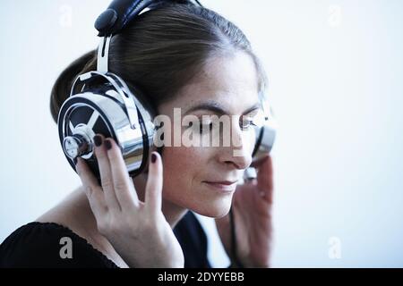 Frau mit einem Satz von Retro-Kopfhörer mit Kabel.Vintage Analog Sound.Frau hört Musik auf ihren Kopfhörern, weißer Hintergrund Stockfoto