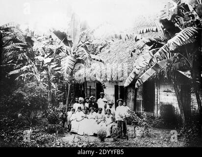 Ein Schwarzweißfoto aus dem frühen 20. Jahrhundert, das eine einheimische Familie in Panama mit ihrer Hütte, ihrem Haus zeigt. Das Land, auf dem sie stehen und leben, wurde untergetaucht, um Platz für den Bau des Panamakanals zu machen. Stockfoto