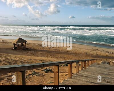 Die Treppe hinunter zu einem wunderschönen Strand in der Nähe Welliges Mittelmeer bei Sonnenuntergang Abendzeit in Skikda Algerien Stockfoto