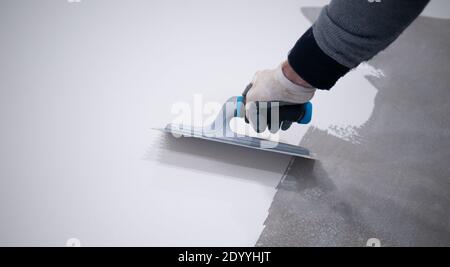 Arbeiter, der einen weißen Eimer aus Epoxidharz auf den Boden aufgibt Stockfoto