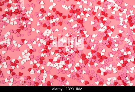 Viele kleine Herzen auf einem rosa Hintergrund. Draufsicht, romantischer Hintergrund. Stockfoto