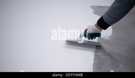 Arbeiter, der einen weißen Eimer aus Epoxidharz auf den Boden aufgibt Stockfoto