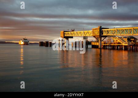 WA18893-00...WASHINGTON - Cross-Sound Fähre Ankunft von Kingston am Edmonds Dock, als die Sonne über dem Puget Sound untergeht. Stockfoto