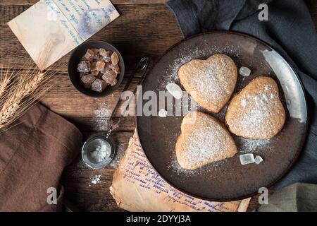 Cookies werden mit Puderzucker auf einem Vintage-Hintergrund bestreut. Stockfoto