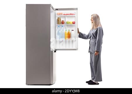 Frau im Pyjama öffnen einen Kühlschrank isoliert auf weißem Hintergrund Stockfoto