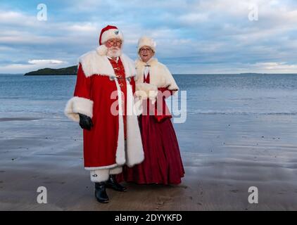 Paar in Weihnachtsmann oder Weihnachtsmann-Kostüme und Mrs Claus-Kostüme am Strand, North Berwick, East Lothian, Schottland, Großbritannien Stockfoto