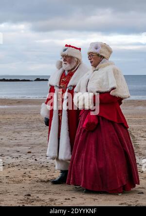 Paar in Weihnachtsmann oder Weihnachtsmann-Kostüme und Mrs Claus-Kostüme am Strand, North Berwick, East Lothian, Schottland, Großbritannien Stockfoto