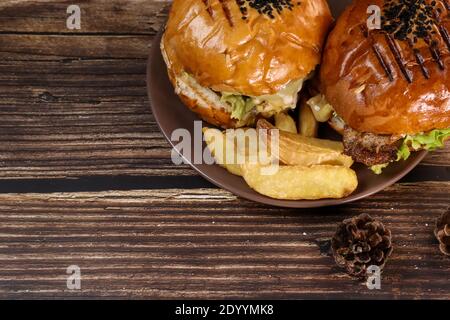 Draufsicht auf zwei frisch gebratene Burger liegen auf einem Teller und einem Holztisch. Saftig gebratenes Abendessen . Stockfoto