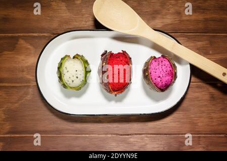 Mexikanische exotische Früchte. Die Pitaya wächst auf einem Kaktus. Die Pitayas sind in weißer Platte über einem Holztisch ausgestellt Stockfoto