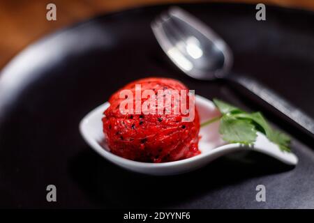 Makro Nahaufnahme zu roten Pitaya exotische mexikanische Früchte auf einem schwarzen Teller. Schwarze Samen Stockfoto